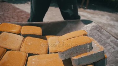 Şantiye, inşaat işçisi kaldırır taş parke gelen el arabası. Ağır çekim