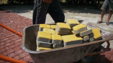 Şantiye, inşaat işçisi kaldırır taş parke gelen el arabası. Ağır çekim
