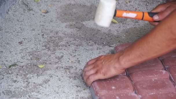 Trabalhador está deitado pedras de pavimentação usando martelo. Movimento lento — Vídeo de Stock