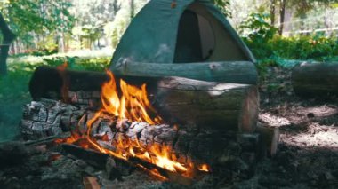 Bir çadır kamp içinde şenlik ateşi Burns ve ormanda günlüğe kaydeder. Ağır çekim