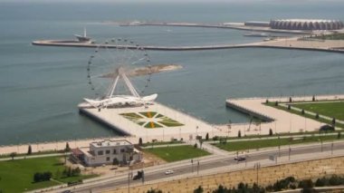 Dönme dolap panoramik manzaralı denize sıfır, yolda araçların trafik döner. Bakü, Azerbaycan. Zaman atlamalı