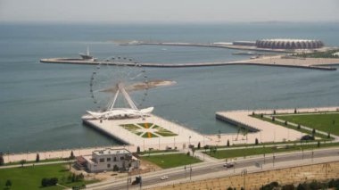 Dönme dolap panoramik manzaralı denize sıfır, yolda araçların trafik döner. Bakü, Azerbaycan. Zaman atlamalı