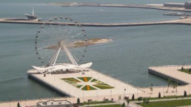Dönme dolap panoramik manzaralı denize sıfır, yolda araçların trafik döner. Bakü, Azerbaycan. Zaman atlamalı