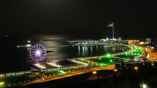 Top View of a Big City at Night, Ferris Wheel on the Background of the Sea and the Moon Path. Движение на дорогах. Расписание — стоковое видео