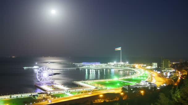 顶视图的一个大城市的夜晚，摩天轮为背景，大海和月球路径。在公路上的交通。时间流逝 — 图库视频影像