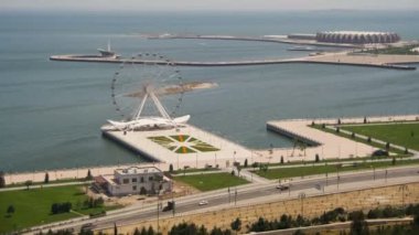 Dönme dolabın manzarası deniz kenarında dönüyor, yoldaki arabaların trafiği. Bakü, Azerbaycan. Zaman Süreleri