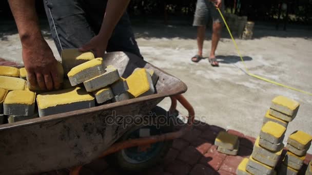 건설 현장, 건설 노동자는 수레에서 포장 하는 돌을 언로드합니다. 슬로우 모션 — 비디오