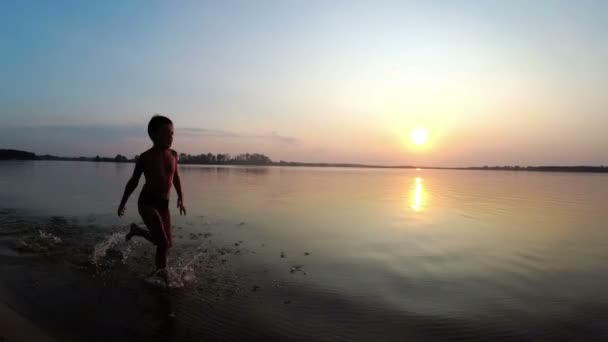 Happy Child court le long de la plage au coucher du soleil. Mouvement lent — Video