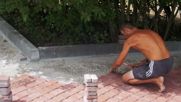 Trabalhador está deitado pedras de pavimentação usando martelo — Vídeo de Stock