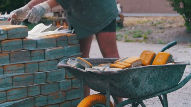 El trabajador carga una piedra de pavimentación de color en la carretilla — Vídeos de Stock