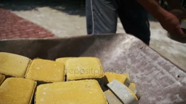 Şantiye, inşaat işçisi kaldırır taş parke gelen el arabası. Ağır çekim