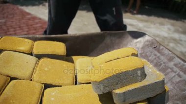 Şantiye, inşaat işçisi kaldırır taş parke gelen el arabası. Ağır çekim