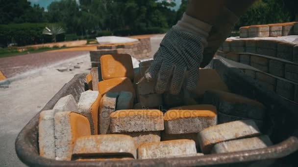 Canteiro de obras, o trabalhador de construção descarrega a pedra pavimentação do carrinho de mão. Movimento lento — Vídeo de Stock