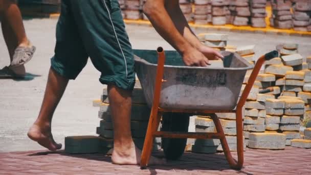 Sitio de construcción, el obrero de construcción descarga el pavimento de piedra de la carretilla. Moción lenta — Vídeo de stock