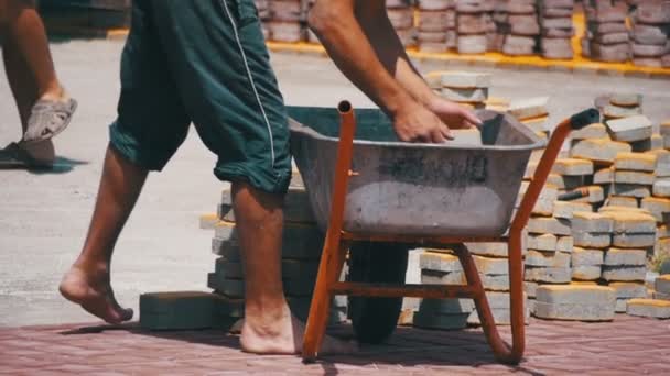 Byggarbetsplatsen, byggarbetaren lossar den sten bana från skottkärra. Slow Motion — Stockvideo