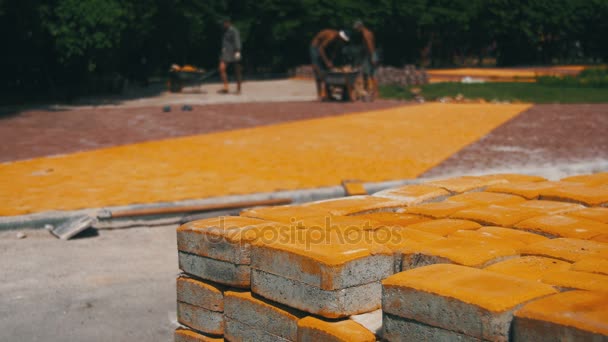 Proces výstavby, opravy chodníku. Pracovníka pokládání kamenné dlažby v city parku — Stock video