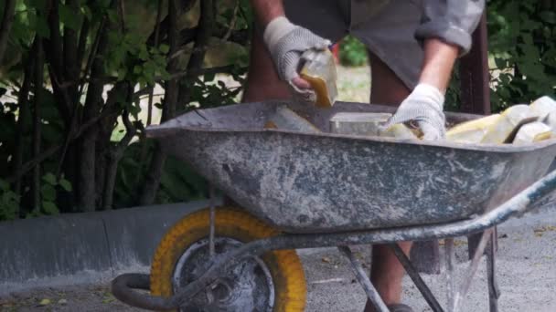 El trabajador carga una piedra de pavimentación de color en la carretilla — Vídeos de Stock