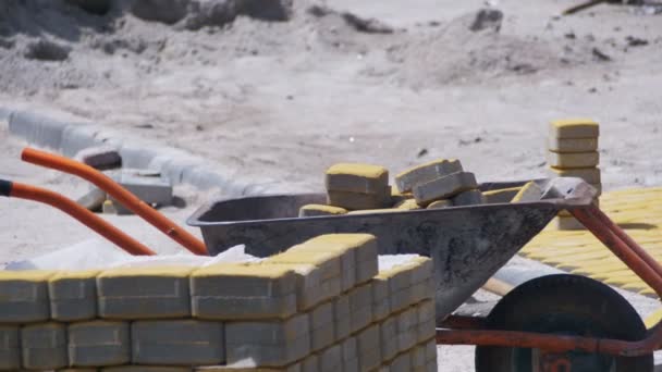 Trabajador de la construcción está conduciendo una carretilla con adoquines en un sitio de construcción — Vídeo de stock