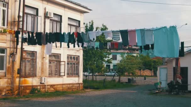Oblečení se naváží a suché na laně v patrové budově v chudé čtvrti města — Stock video