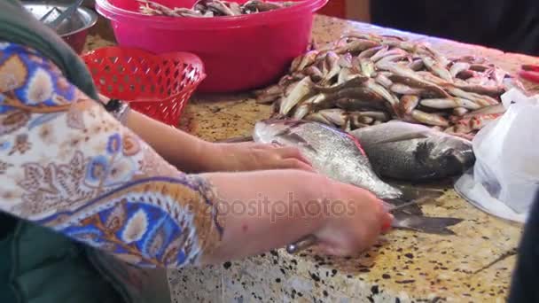 Женщина чистит и режет свежую рыбу на рыбном рынке — стоковое видео