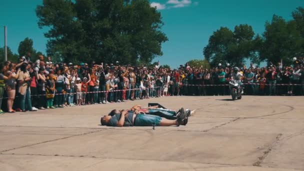 Moto skok na trampolíně prostřednictvím ležící lidi. Moto trik. Kousek Moto Show. Zpomalený pohyb — Stock video