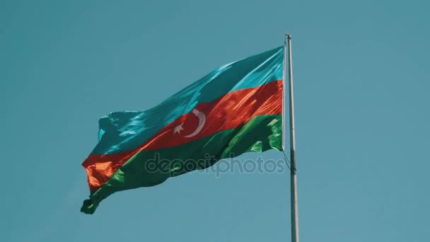 Bandera de Azerbaiyán en el asta de la bandera ondeando en el viento contra el cielo azul — Vídeos de Stock