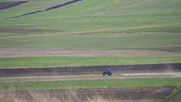 El tractor está conduciendo a través del campo en las montañas — Vídeos de Stock