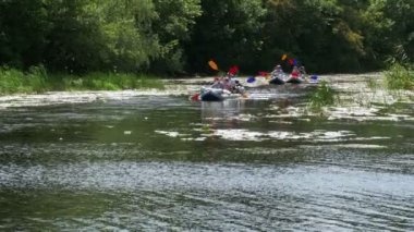 Nehirde yüzen insanlar uzun bir teknede, kanoda. Turizm