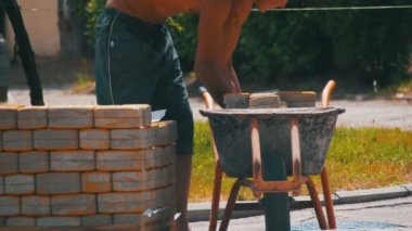 İşçi el arabası içinde renkli bir kaldırım taşı yükler