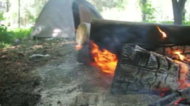 Bir çadır kamp içinde şenlik ateşi Burns ve ormanda günlüğe kaydeder. Ağır çekim