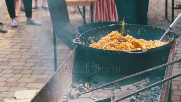 Pilaf uzbeko se cocina en un caldero sobre un incendio en la calle — Vídeos de Stock