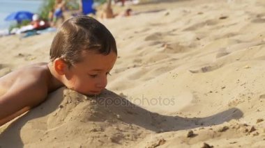 Çocuk ağır çekimde sahilde kum ile oynuyor