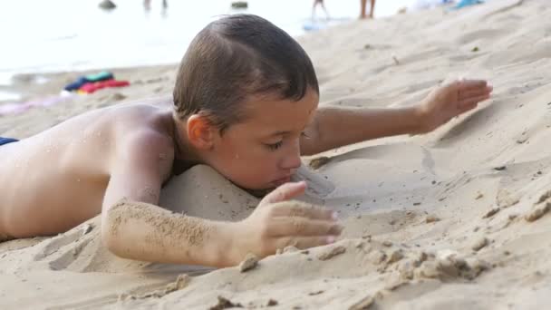 Il bambino sta giocando con la sabbia sulla spiaggia — Video Stock