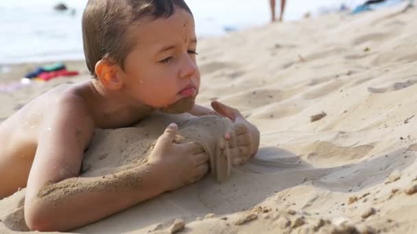 Ребенок играет с песком на пляже в медленном движении — стоковое видео