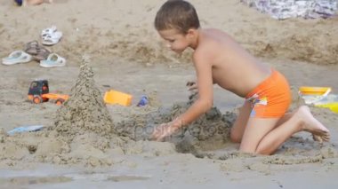 Çocuk ağır çekimde sahilde kum kale inşa ediyor