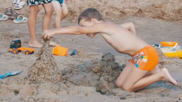 Niño está construyendo un castillo de arena en la playa en cámara lenta — Vídeo de stock