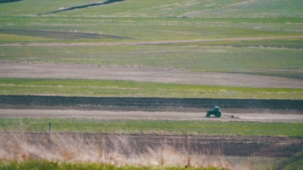 Traktorn är körkort via fältet i bergen — Stockvideo