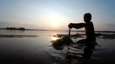 Küçük çocuk yapılar bir kum kale günbatımında siluet