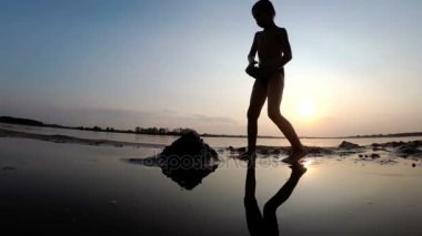 Sahilde günbatımı kum kale inşa bir çocuk silüeti