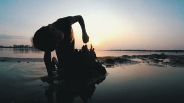 Sahilde günbatımı kum kale inşa bir çocuk silüeti