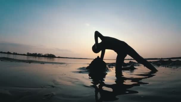 Silhouette eines Kindes am Strand, das bei Sonnenuntergang eine Sandburg baut — Stockvideo