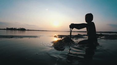 Sahilde günbatımı kum kale inşa bir çocuk silüeti