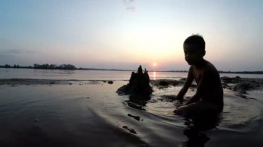 Küçük çocuk yapılar bir kum kale günbatımında siluet