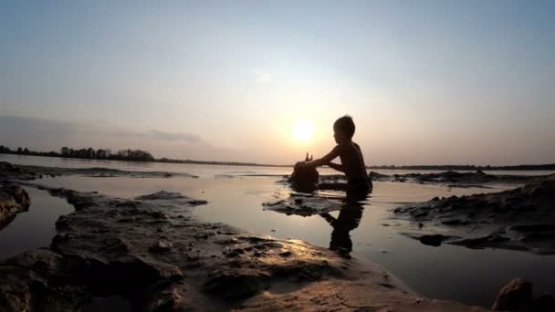 Silhouet van een kind op het strand een Sand Castle Building bij zonsondergang — Stockvideo