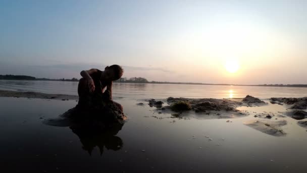 Silhouette Petit garçon construit un château de sable au coucher du soleil — Video