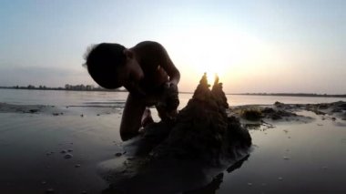 Sahilde günbatımı kum kale inşa bir çocuk silüeti