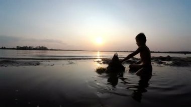 Küçük çocuk yapılar bir kum kale günbatımında siluet