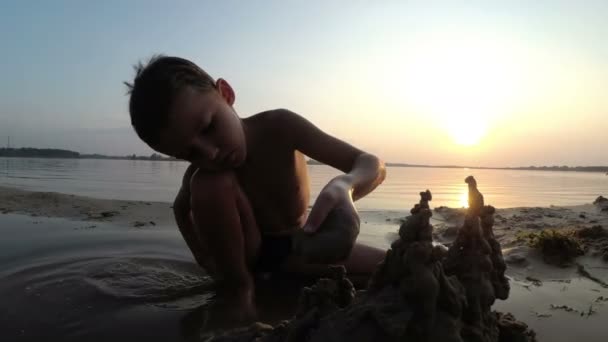 Silhouette Petit garçon construit un château de sable au coucher du soleil 