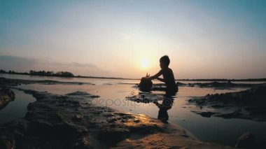 Küçük çocuk yapılar bir kum kale günbatımında siluet