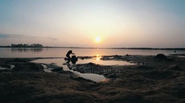 Sahilde günbatımı kum kale inşa bir çocuk silüeti